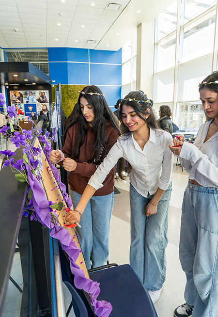 three students interacting with an activity board