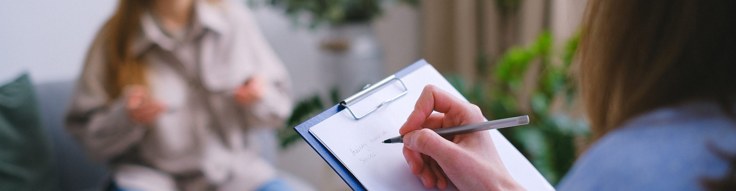 Counsellor writing notes down on a clipboard