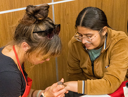 artist doing henna art on a student