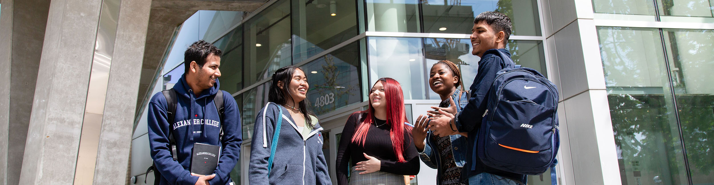 a group of smiling students standing outside Alexander College