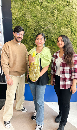 three students holding a durian