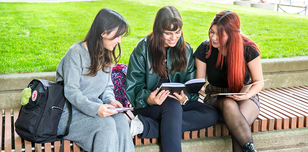 three students reading outside