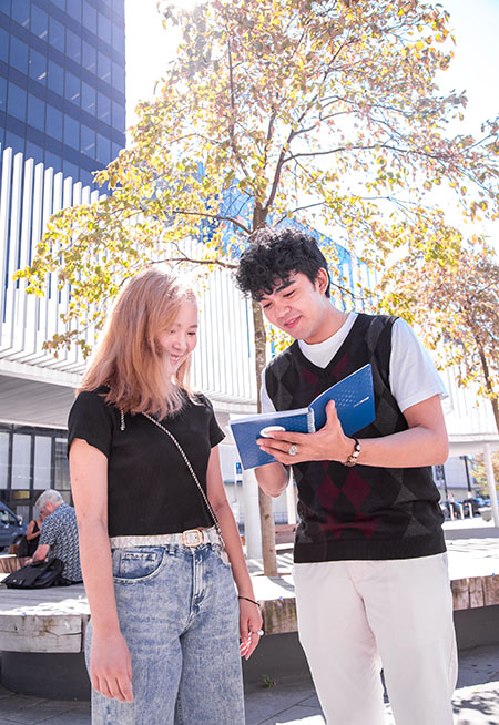 student looking another student's notebook outside
